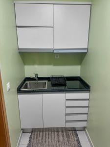 a small kitchen with a sink and white cabinets at AP2B Praia in Praia