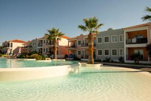 a swimming pool with palm trees and houses at Eriphilly Studios & Apartments in Mythimna