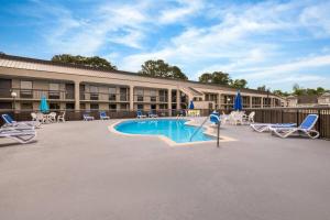 a resort with a pool and chairs and a building at Days Inn by Wyndham Norfolk Airport in Norfolk