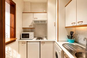 a kitchen with white cabinets and a sink and a microwave at Apartamentos Vértice Bib Rambla in Seville