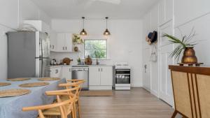 a kitchen with white cabinets and a table and chairs at Bruns Beach Shack in Brunswick Heads