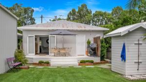 a small white house with a table and an umbrella at Bruns Beach Shack in Brunswick Heads +3 photos