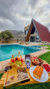 a table with food on it next to a pool at Apex Hills تلال القمة in Dār Sawdāʼ
