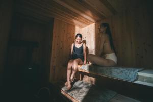 two women sitting on a ledge in a sauna at Earthboat Ueda Onsen in Nagano