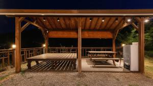 a wooden gazebo with a picnic table and a bench at Gapyeong Swimteo Pet Pension in Gapyeong