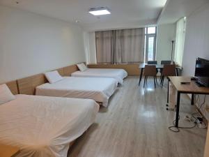 a room with four beds and a table and a desk at Incheon Airport Yeongjong Guesthouse in Incheon
