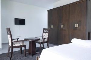a bedroom with a bed and a table and chairs at Tcc - Skysuites in Accra