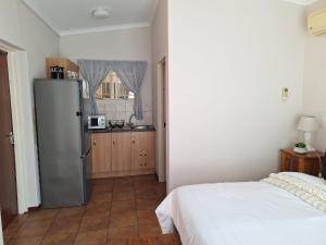 a kitchen with a refrigerator and a bed in a room at Cozy Room in Ellisras