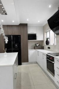 a kitchen with white cabinets and a black appliance at The Seamless Oasis in Cape Town