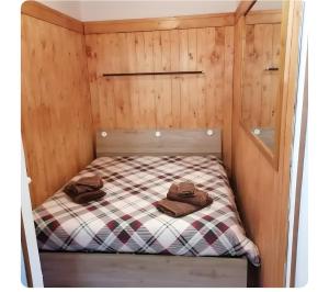 a small bed in a wooden cabin with two hats on it at Appartamento Sestriere in Sestriere