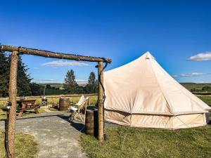 a tent in the grass with a table and a bench at The Belle Tent in Otterburn