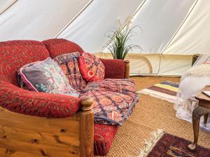 a couch with pillows in a room with a tent at The Belle Tent in Otterburn +2 photos