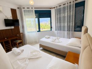 a hotel room with two beds and a window at Hotel Palma in Gjirokastër