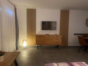 a living room with a television on a wooden dresser at Ferienwohnung Fein in Bad Sachsa