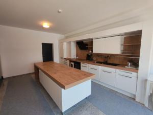 a kitchen with white cabinets and a wooden counter top at MarchfeldStay in Gänserndorf