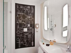 a bathroom with a black and white pattern on the wall at ibis Paris Porte de Clichy Centre in Clichy +61 photos