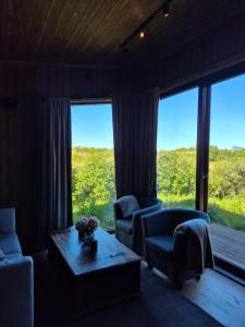 a living room with two chairs and a table and large windows at Cabin Aurora Borealis in Sommarøy +18 photos