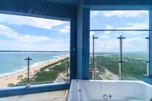 a bath tub in a bathroom with a view of the beach at 플럼바고올스위트1809 in Sangun-ni +2 photos