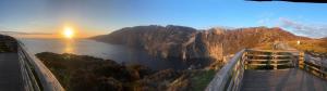 a view of a mountain with the sun setting over the water at Donegal Cottage in Inver