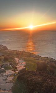 a sunset on a golf course with the ocean at Donegal Cottage in Inver