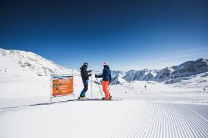 two people on skis standing next to a sign in the snow at Living & Spa Vitalhotel Edelweiss in Neustift im Stubaital