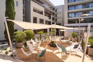 a patio with chairs and umbrellas in front of a building at Hotel Garden Istra Plava Laguna in Umag