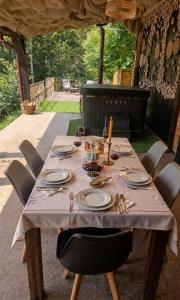 a wooden table with plates and utensils on it at Porumbacu Retreat-Cabana Forest A-frame și Chalet Max cu jacuzzi și piscină sezonieră, pe malul râului ,în apropiere de Transfăgărășan, Sibiu in Porumbacu de Sus