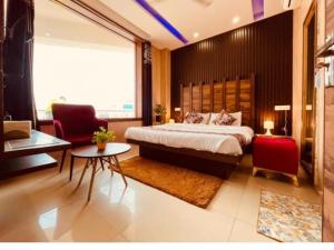 a bedroom with a bed and two chairs and a table at Hotel PG Grand in Mohali +5 photos