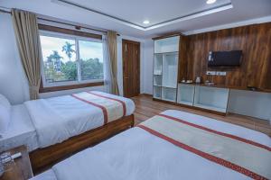 a hotel room with two beds and a television at Batika Resort Sauraha in Sauraha +53 photos