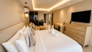 ein Schlafzimmer mit einem großen weißen Bett und einem Flachbildfernseher in der Unterkunft ROZ MARINE Boutique Hotel in Bophut 