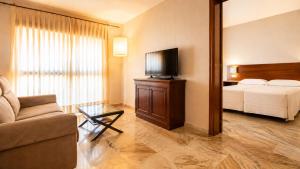 a hotel room with a bed and a television at Apartamentos Vértice Bib Rambla in Seville