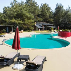 a swimming pool with chairs and a red umbrella at Mossa Afkule Kayaköy in Fethiye