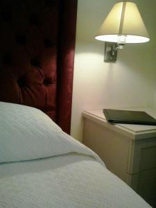 a bed with a lamp on a nightstand next to a bed sidx sidx sidx at Hotel Miramare in Lavagna