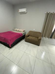 a bed and a chair in a room at silencioso e aconchegante in Rio Verde