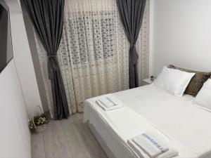 a bedroom with a white bed and a window at Transfăgărașean Gateway in Curtea de Argeş