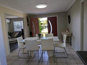 a dining room with a table and white chairs at The Pine Rest - Spacious & Central Haven in Brendale