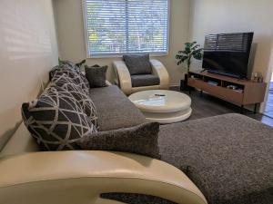 a living room with a couch and a tv at The Pine Rest - Spacious & Central Haven in Brendale