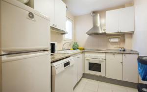 a kitchen with white cabinets and a refrigerator at Miquel 1 – Piso con Parking y Wifi en el Centro in Tossa de Mar