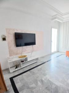 a white living room with a flat screen tv on a wall at galaxy home in Nabeul