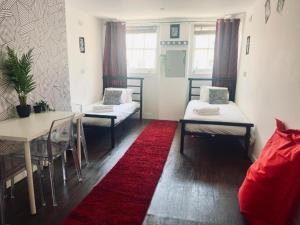 a room with two beds and a table and a red rug at Big Group Stays in Brighton & Hove