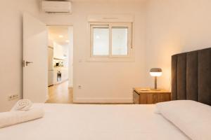 a white bedroom with a bed and a window at Panther Home Manantial in El Puerto de Santa María