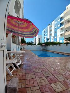 a patio with an umbrella and chairs and a pool at galaxy home in Nabeul