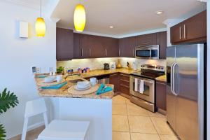 a kitchen with wooden cabinets and stainless steel appliances at Modern Beachfront Condo with Pool - Sapphire 307 in Christ Church