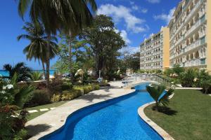 a bridge over a swimming pool next to a building at Modern Beachfront Condo with Pool - Sapphire 307 in Christ Church