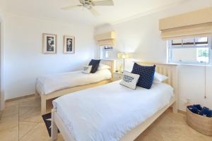 two beds in a room with white walls at Modern Beachfront Condo with Pool - Sapphire 307 in Christ Church