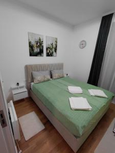 a bedroom with a green bed with towels on it at Prolink Residence Podgorica in Podgorica +14 photos
