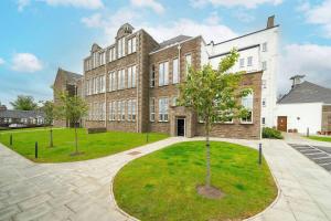 a large brick building with a tree in front of it at Whinny Brae in Broughty Ferry
