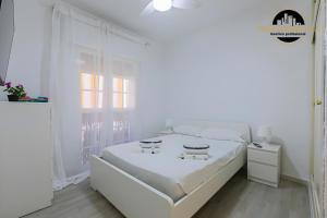 a white bedroom with a white bed and a window at El Bajondillo Apartment in Torremolinos +11 photos