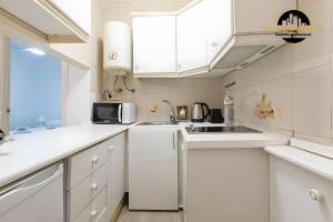 a white kitchen with a sink and a microwave at El Bajondillo Apartment in Torremolinos
