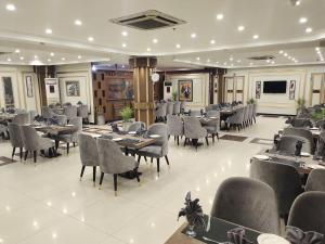 a restaurant with tables and chairs in a room at Hotel the Jeeven's in Sialkot